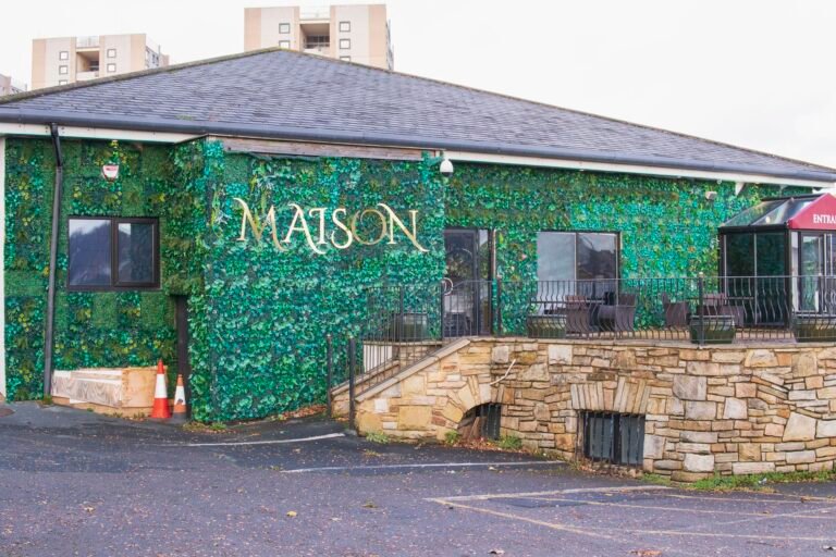 Exterior of The Maison Bradford wedding venue in BD5, showing the floral green wall and main entrance used by couples across Bradford, Leeds and West Yorkshire.