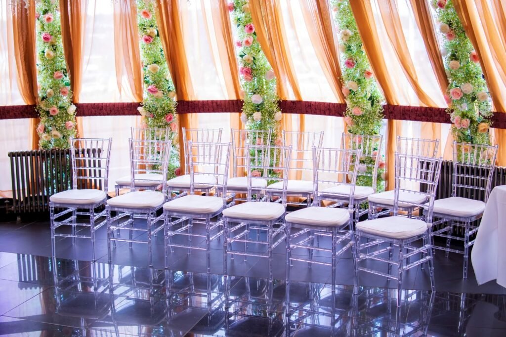 Rows of clear chiavari chairs arranged for a wedding or nikah ceremony at The Maison Bradford with floral backdrop and draped curtains.