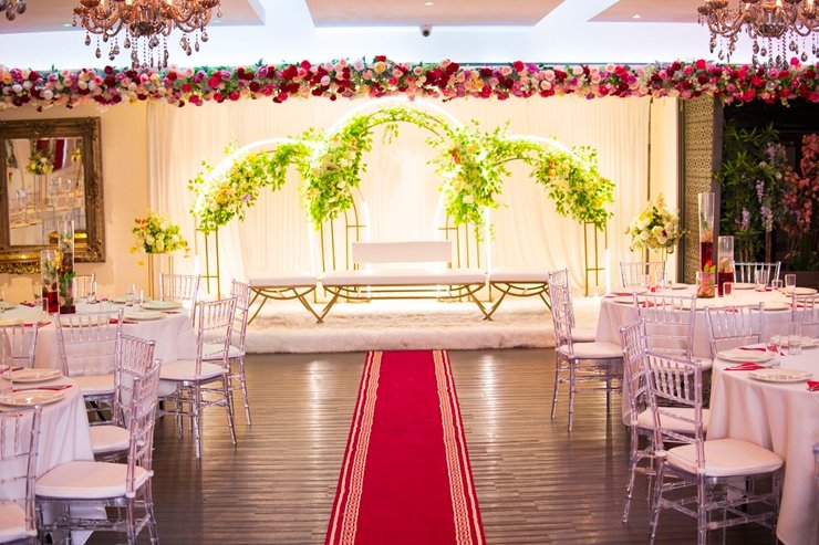 Grand Walima reception stage with a red carpet and floral arch.