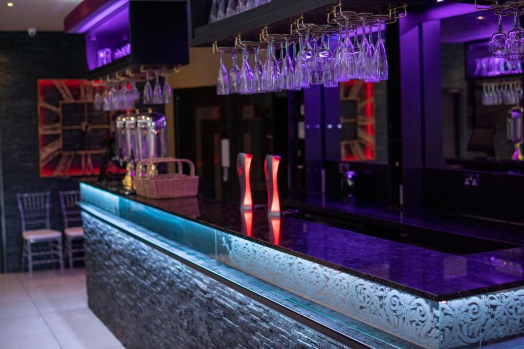Bar and lounge area at The Maison Bradford with glass displays and ambient purple lighting, prepared for Ramadan iftars and Eid celebrations.