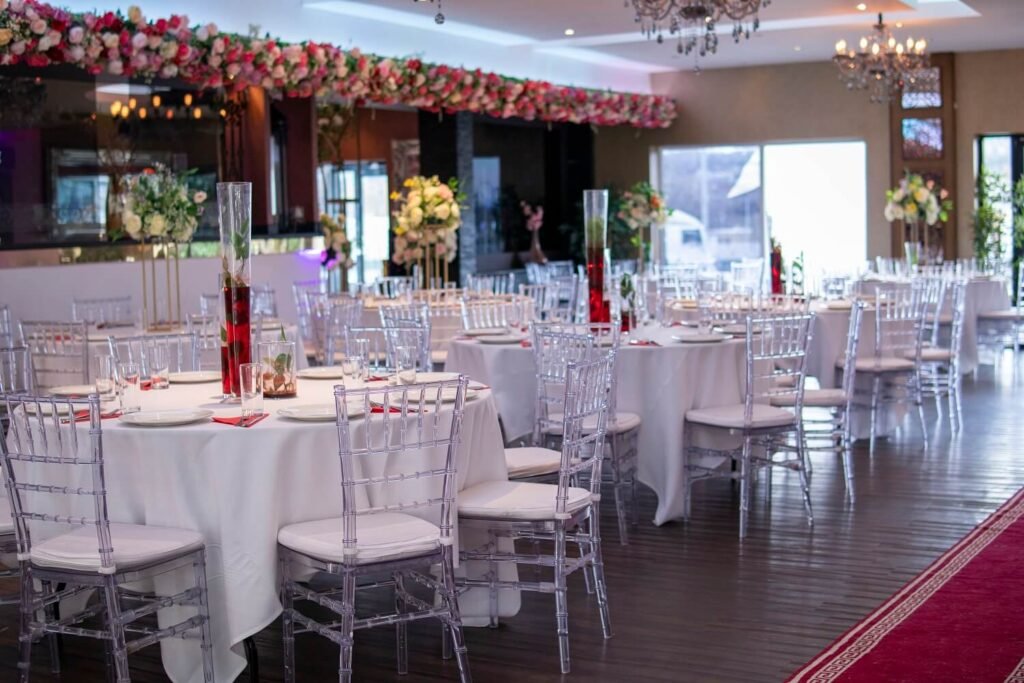 Large capacity wedding hall in Bradford showing multiple round tables set for 300 guests with elegant red carpet aisle and chandelier lighting.