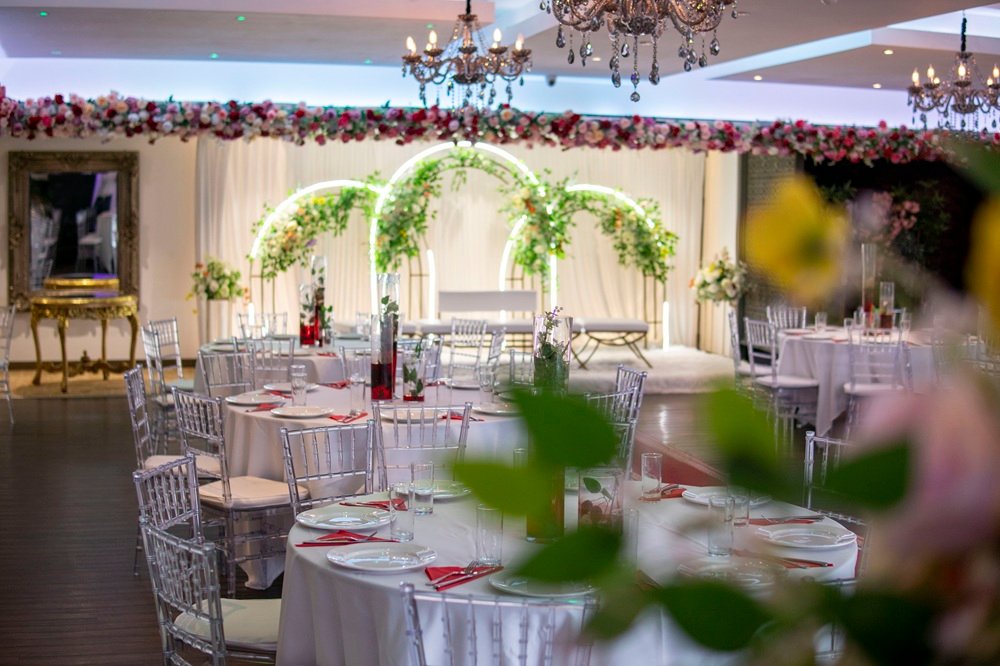Wedding hall at The Maison Bradford with floral arches, clear chairs and elegant table settings, showing how the venue transforms for celebrations.