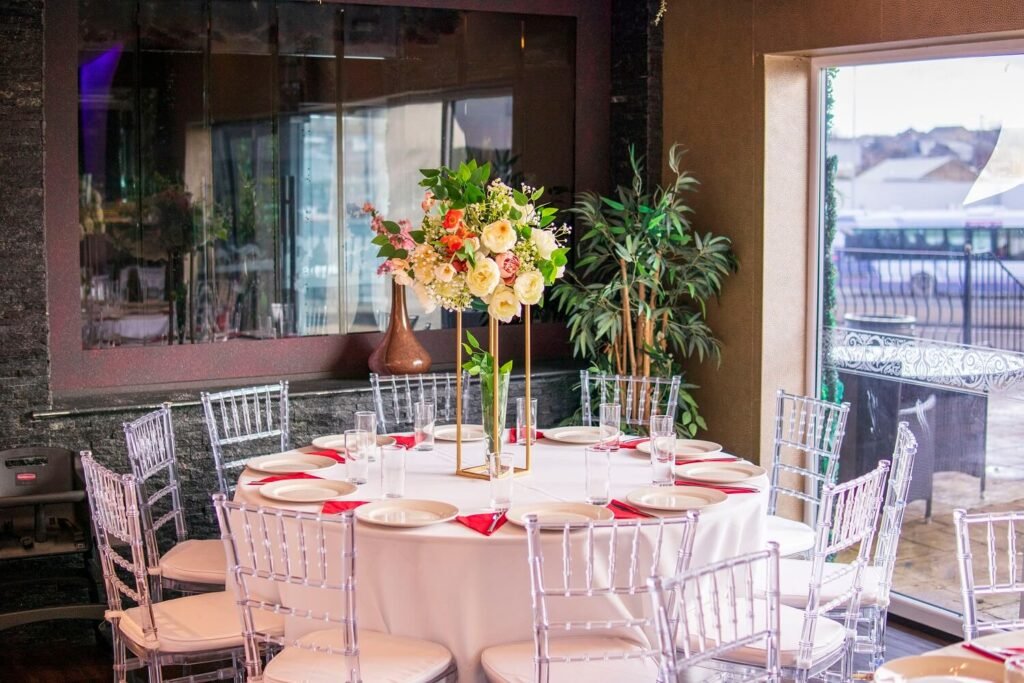 Round table setup with clear chairs and floral centrepiece at The Maison Bradford, prepared for weddings from 50 to 300 guests.