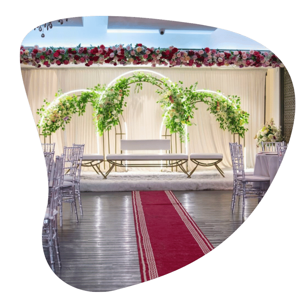 Asian wedding stage setup in the main hall at The Maison Bradford with floral arches, banquet seating, and red aisle runner for mehndi, nikah, or walima events.