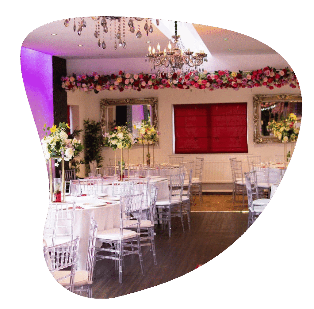 Luxury banqueting hall in Bradford set up for a wedding breakfast with crystal chandeliers, floral centerpieces, and clear Chiavari chairs.
